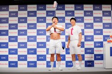 「プロティンダイエット MCTプラス」とトレーニング器具を合体させたアイテムを受け取ったチョコレートプラネット松尾（左）。