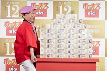 12億円相当というダミーの紙幣の山を持ち上げようとするダチョウ倶楽部・上島。