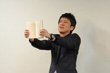 自著の紙面を見せるブラックマヨネーズ吉田。