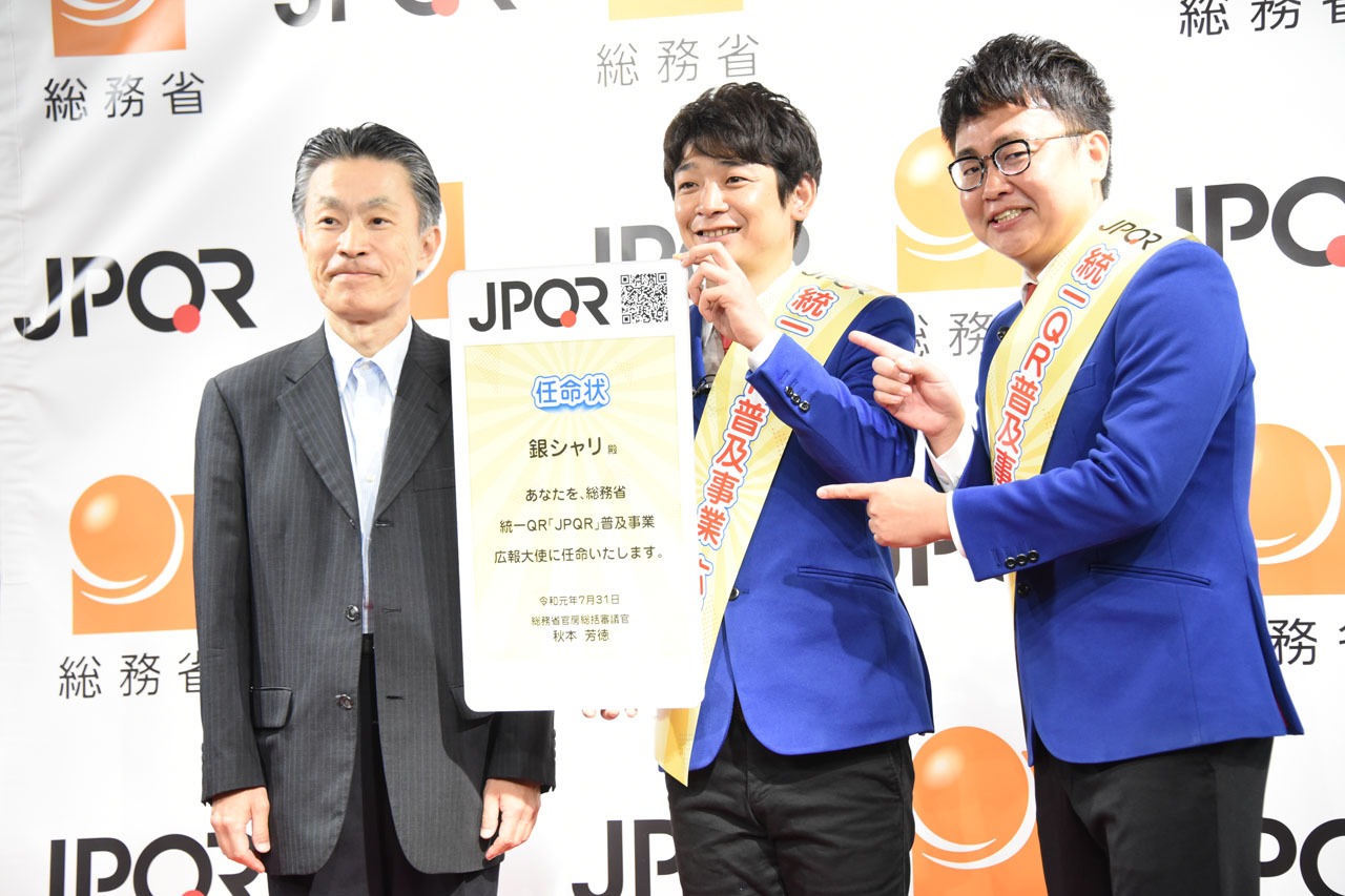 JPQR広報大使に就任した銀シャリと総括審議官・秋本芳徳氏（左）。