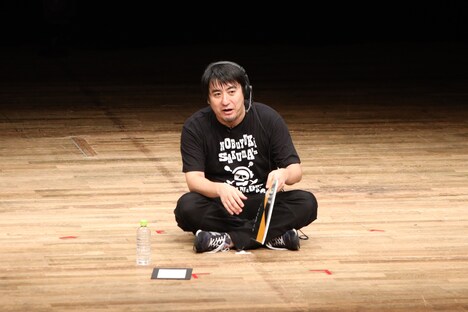 「カンペ」のコーナーを、普段テレビ番組制作の際と同様の地べた座りスタイルで披露する佐久間P。