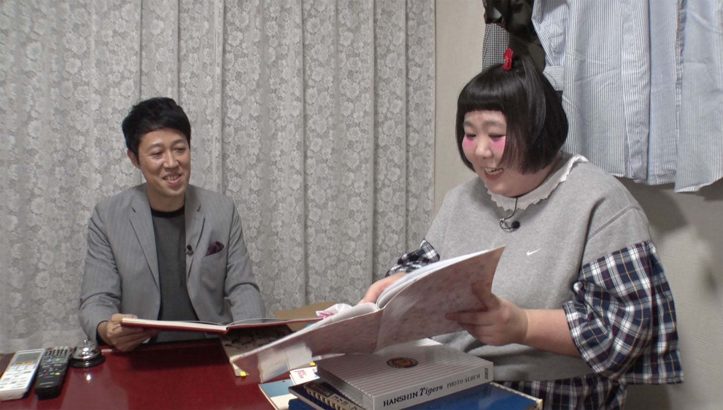 今別府直之のアルバムを眺める小籔千豊（左）と酒井藍（右）。(c)MBS