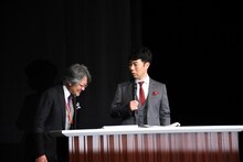 井上肇氏（左）に厳しい態度をとる藤井隆（右）。