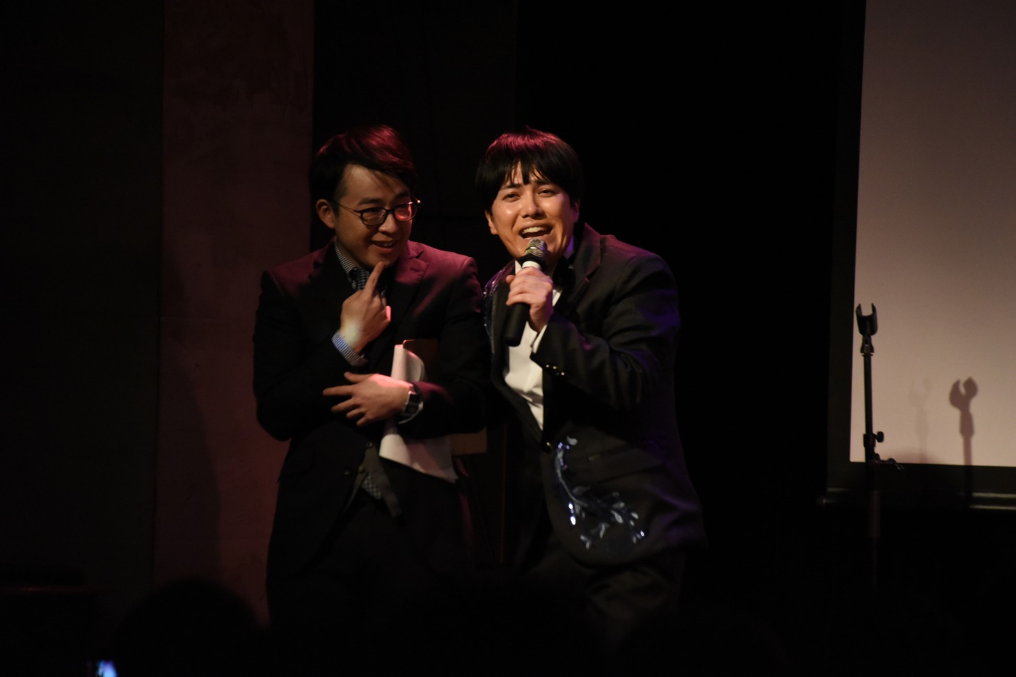 タッカーノの肩を抱いて「お前だけが死ぬほど好きさ」と歌う溜口（右）。