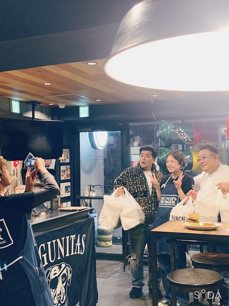 ハンバーガー100個を購入し、店員と記念撮影するサンドウィッチマン。