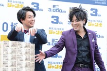 3億円をピアノに見立てて弾くぺこぱシュウペイ（左）。