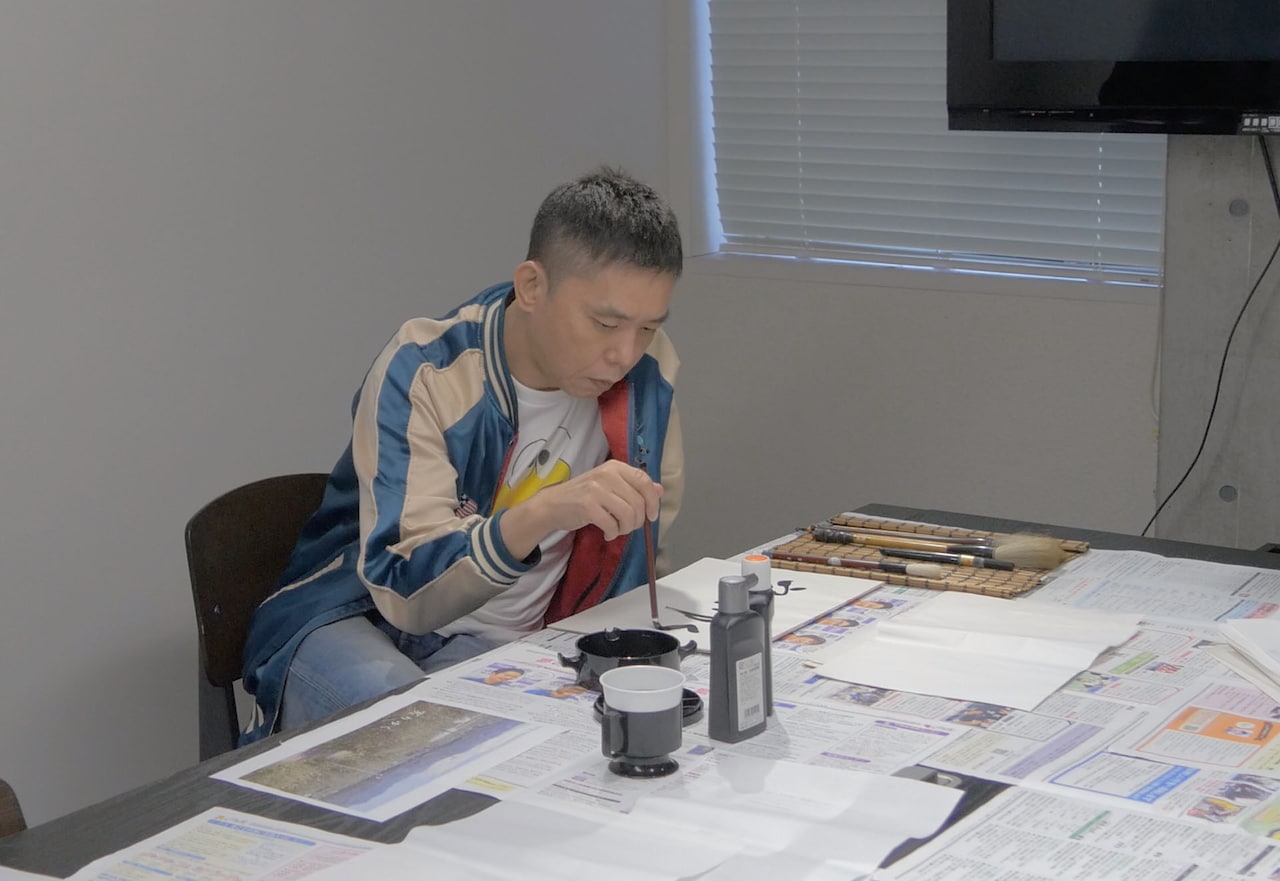 「実りゆく」の題字を書く爆笑問題・太田・