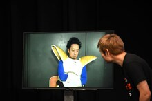 背景にあるドアノブを衣装で隠すR藤本。