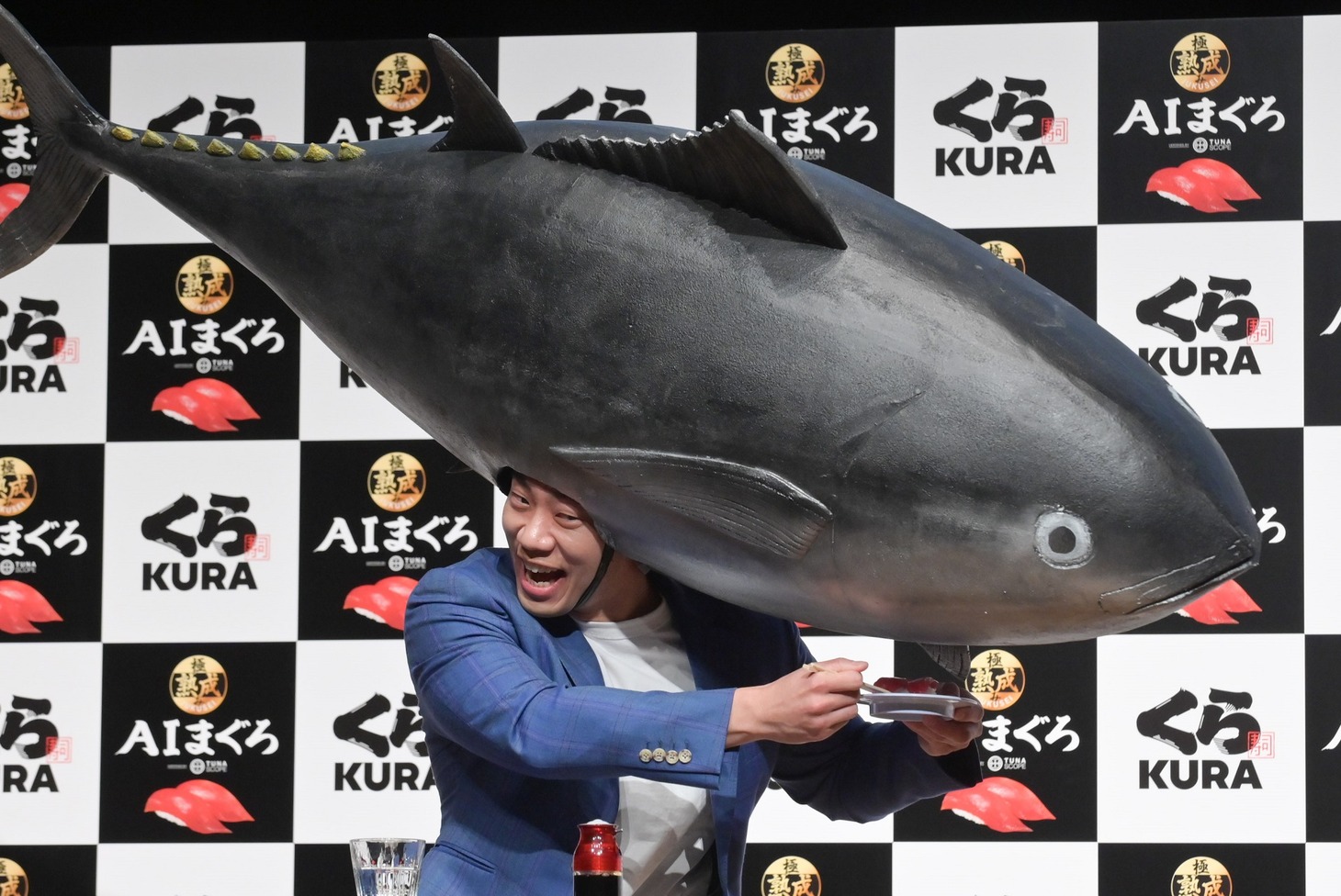 被り物のマグロに寿司を食べさせようとするミルクボーイ駒場。