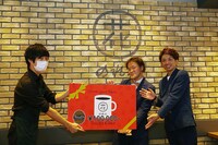 「第1回 笑ラッテ飲んでタグって大賞」の特典を受け取るアインシュタイン（右）。