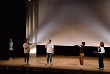 オープニングで一度舞台袖に引っ込められ、ドランクドラゴンとオアシズのトークをこっそり見守るおぎやはぎ小木（左端）。その後、小木の登場シーンが改めて設けられた。