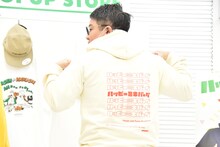 パーカーのバックプリントを見せるミキ昴生。