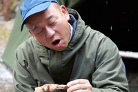 雪が降る中、骨付き豚肉に「バカまぶし」をまぶして食べるバイきんぐ西村。