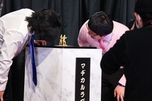 「ど～んと優勝記念像」を凝視するマヂカルラブリー。