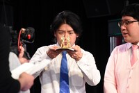 「ど～んと優勝記念像」を凝視するマヂカルラブリー野田クリスタル（左）。