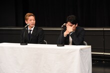 手で顔を覆うニューヨーク屋敷（右）。