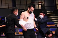 おーちゃん不在のため記者役の男性にTシャツを破るのを手伝ってもらうバビロンのノリ（左）と千葉（中央）。