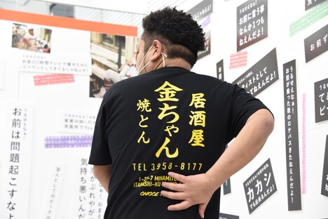 居酒屋金ちゃんTシャツを紹介する金ちゃん。