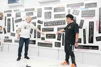 壁に飾られているダメ出しを紹介する鬼越トマホーク。