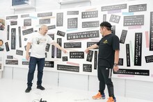 壁に飾られているダメ出しを紹介する鬼越トマホーク。