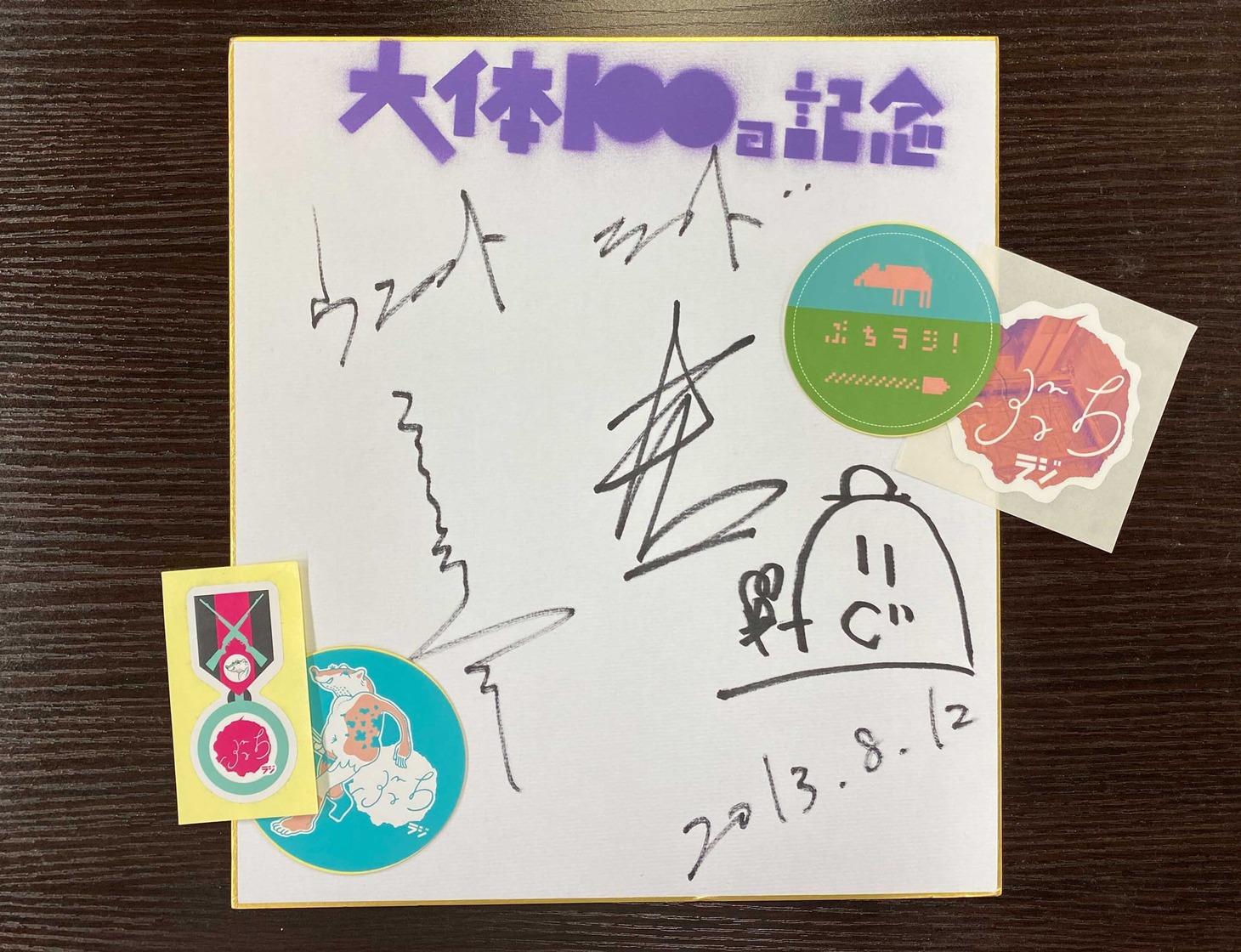 「大体100回記念」の色紙と番組歴代ステッカーの一部。