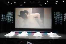 ハリウッドザコシショウ（会場スクリーン）と4人のプレイヤー。