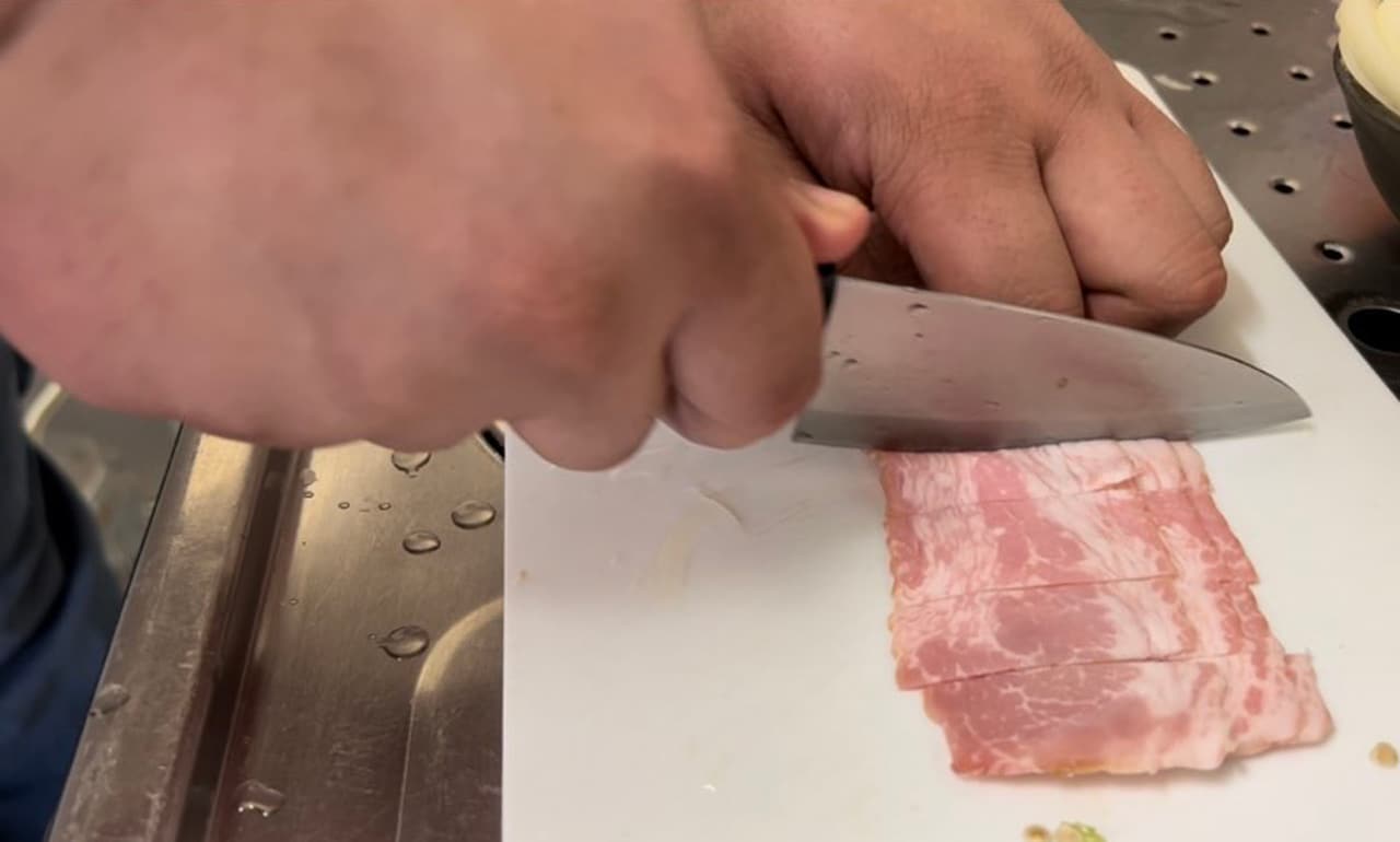ベーコンをカットする大鶴肥満。
