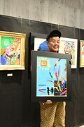 100万円の値を付けた作品を手にするとろサーモン久保田。