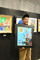 100万円の値を付けた作品を手にするとろサーモン久保田。