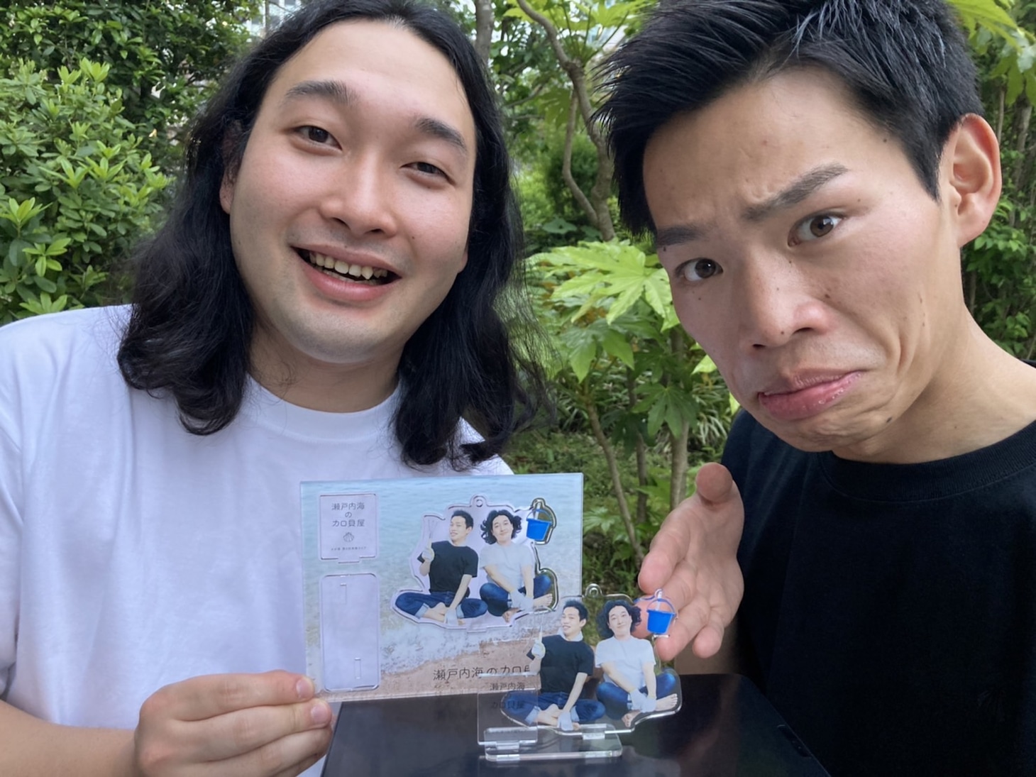 「瀬戸内海のカロ貝屋」のオフィシャルグッズを持ったかが屋。