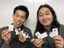 「瀬戸内海のカロ貝屋」のオフィシャルグッズを持ったかが屋。