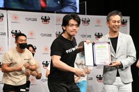 アンバサダーの任命状を受け取りポーズを決めるマヂカルラブリー・野田クリスタル（手前左）。