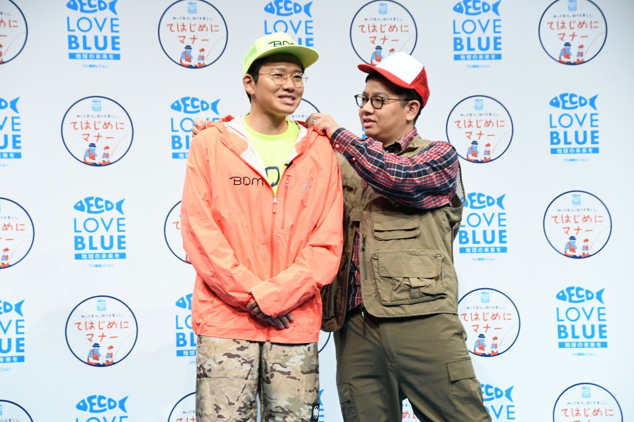 釣りマナー向上大使のミキ亜生（左）の衣装を整えサポートする、釣りマナー向上サポート大使のミキ昴生（右）。