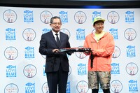 名前入りのライフジャケットを贈呈される釣りマナー向上大使のミキ亜生。