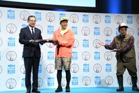 日本釣用品工業会の会長・大村一仁氏（左）とミキ亜生（中央）の写真撮影をサポートするミキ昴生（右）。