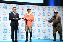 日本釣用品工業会の会長・大村一仁氏（左）とミキ亜生（中央）の写真撮影をサポートするミキ昴生（右）。