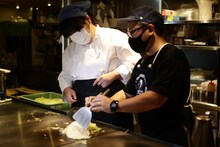 お好み焼きを作るぼる塾あんり（左）。