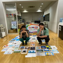 リスナーから届いた暑中見舞いに囲まれるロングコートダディ。