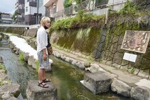 「迷宮グルメ 異郷の駅前食堂」で、川の上に渡された飛べるのかどうか微妙な距離の石を前にするヒロシ。(c)BS朝日
