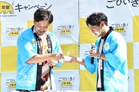 試食の際、平子（左）が「魚カツカレー」をよそって、まず酒井（右）に手渡したワンシーン。