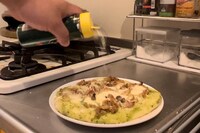 焼き上がったピザに粉チーズをかける。