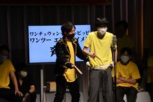 人間横丁・山田（右）に「ワンチュウォンチュピッピッピワンツー エンタテイメン」を教えるスカチャン・ヤジマリー（左）。