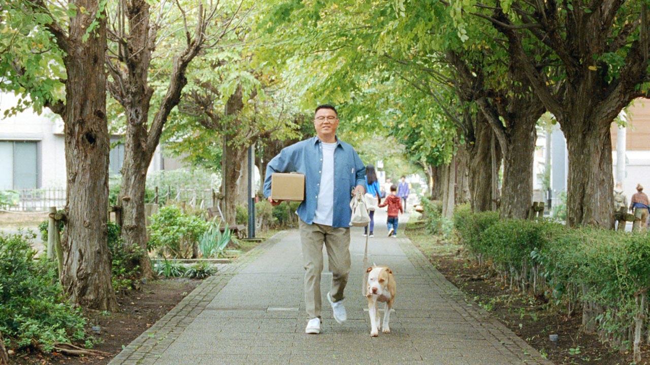 「ゆうパック ご近所散歩中・驚きの事実／安い」編より、荷物を小脇に抱えるシソンヌ長谷川。