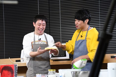 森田の手の甲に乗せたスポンジに生クリームを塗る東ブクロ。