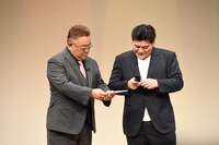 ガラケーでも投票用QRコードを読み取れるのか確かめるサンドウィッチマン富澤。