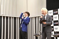 最後の質問の場面でファッションのポイントを聞こうとした記者がほかの記者に質問を譲ったのを見逃さず、「そりゃ譲るわ！」と三四郎・小宮（左）。