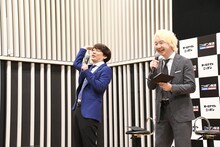 最後の質問の場面でファッションのポイントを聞こうとした記者がほかの記者に質問を譲ったのを見逃さず、「そりゃ譲るわ！」と三四郎・小宮（左）。