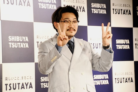 テレビカメラに向かってピースサインを前に出すオズワルド伊藤。