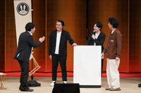 平成ノブシコブシ徳井が登場した際、みんなが立っているから自分も立とうとしたところ、イスが引っかかってしまったロングコートダディ兎（左）。