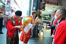 商店街の人たちに花をもらう吉田裕とアキ。